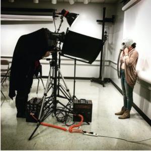 Students using specialized photography equipment. Interestingly, the subject of the photo they are taking is wearing an old fashioned gasmask.